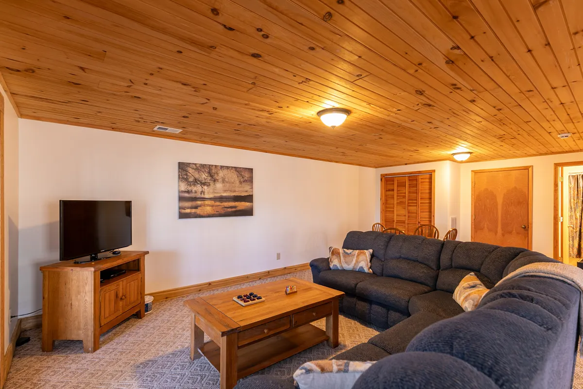 A comfy lounge setup with a sectional sofa facing a TV, coffee table in the center, and stylish wall art. The environment feels warm and perfect for gathering, sharing stories, or settling in for a movie night after a day outdoors.