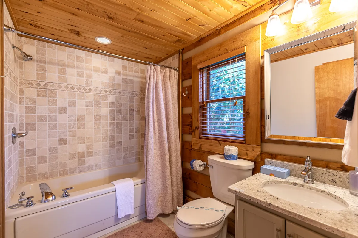 A tranquil bathroom with a deep bathtub, wooden walls, and a window letting in soothing natural light. The space is perfect for unwinding with a relaxing bath after a day of adventure.