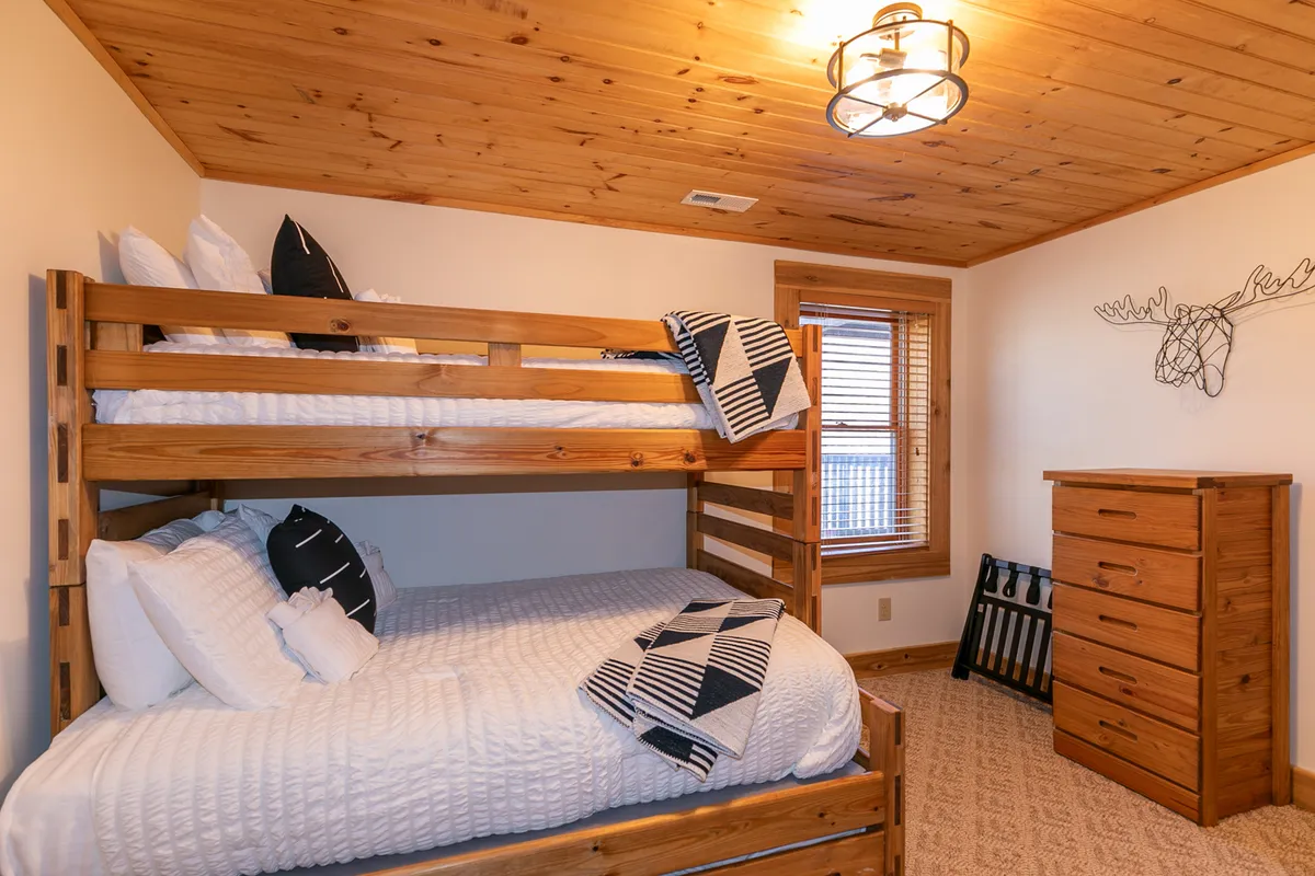A kid-friendly bunk room featuring sturdy wooden bunk beds, a matching dresser, and playful wall decor. The space is designed to be both functional and fun, offering a perfect retreat for children or extra guests.